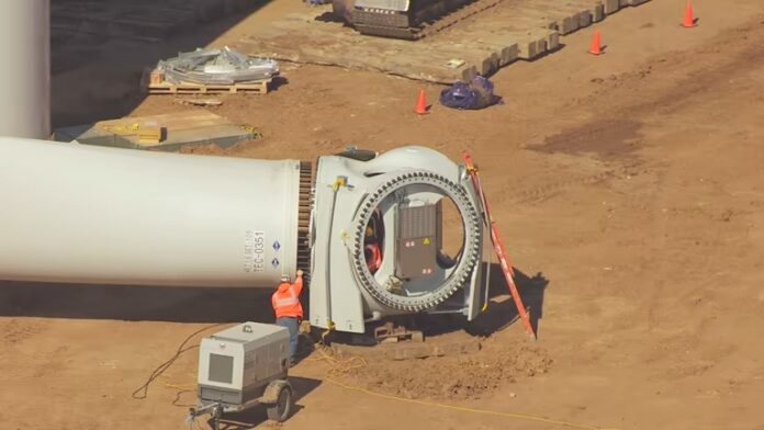 aerial-view-of-workers-on-ground-fitting-blade-to-hub-of-wind-turbine-generator-green-skill-hub